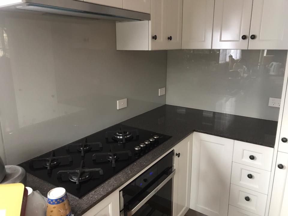 A Kitchen With a Black Stove Top Oven and White Cabinets — Swift Glass & Aluminium In Woolgoolga, NSW