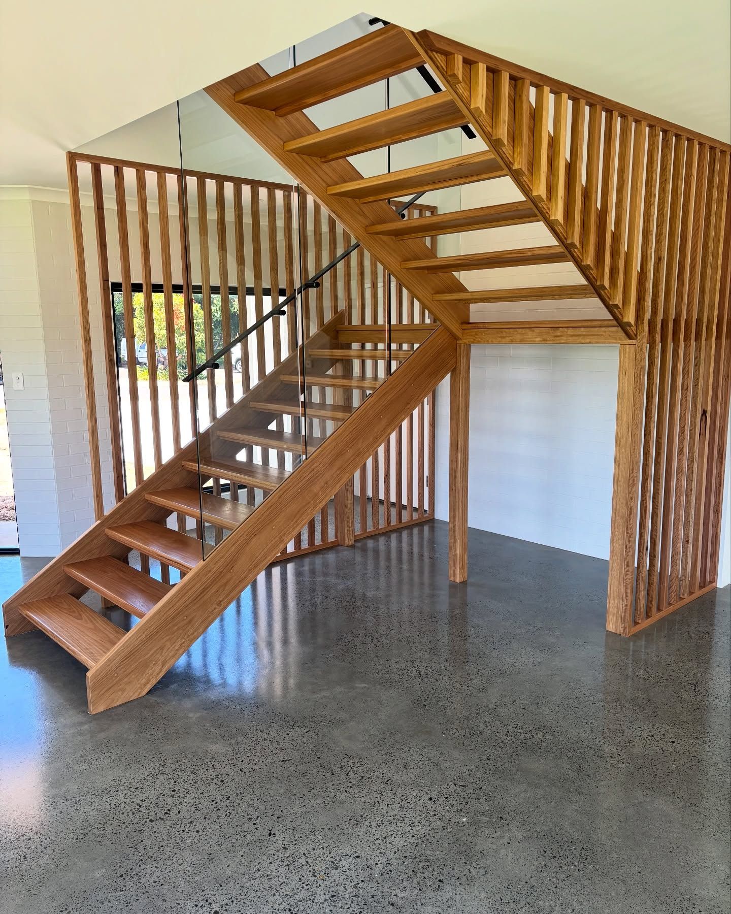A Wooden Staircase in a Room With a Concrete Floor β Swift Glass & Aluminium In Woolgoolga, NSW