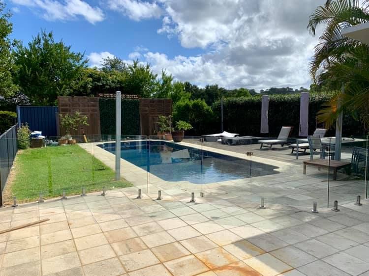 A Large Swimming Pool is Surrounded by Lawn Chairs and a Fence β Swift Glass & Aluminium In Woolgoolga, NSW