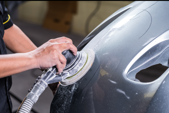 A person is polishing a red car with a machine.