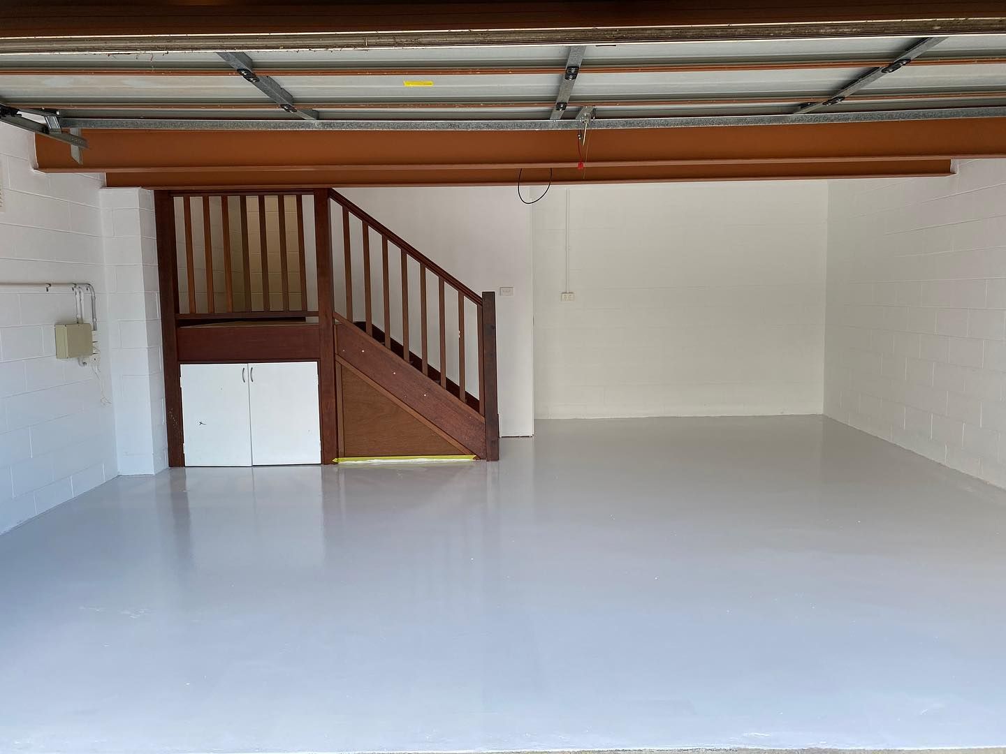 A White-painted Garage With Stairs. Light Gray Floor, White Walls, Brown Trim — All Coast Painting in Tweed Heads South, NSW