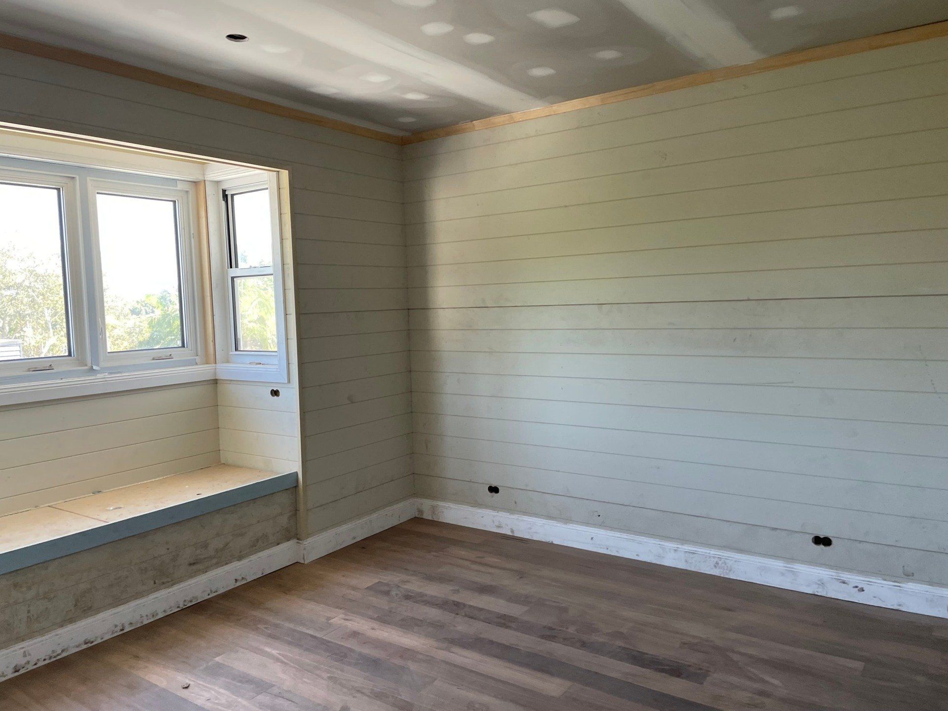 Empty Room With Wood-look Floor, Window, and Light Green Panelled Walls — All Coast Painting in Tweed Heads South, NSW