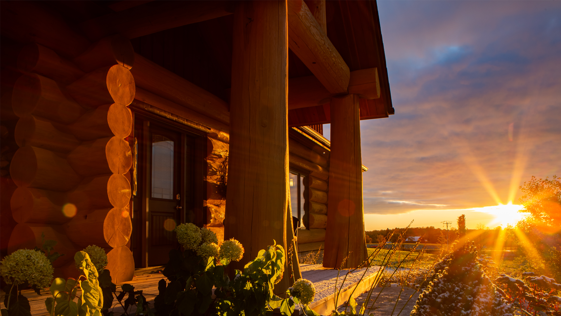 Sunset view of a log home with flared trunks at the entrance.