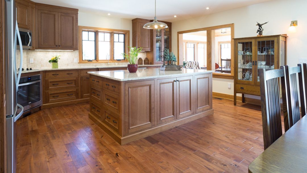 Large kitchen with a walk around island showing lots of beautiful wood flooring and matching cabinets.