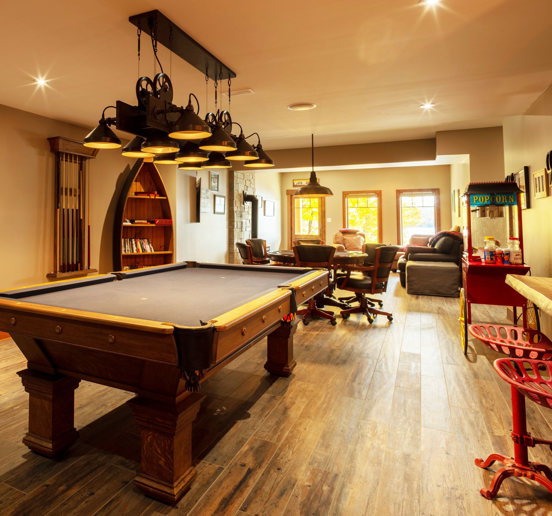 Large, bright, open room with pool table and card table, bar with stools.