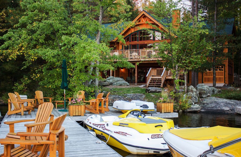 Large dock with Muskoka chairs and a variety of boats and jet skis.