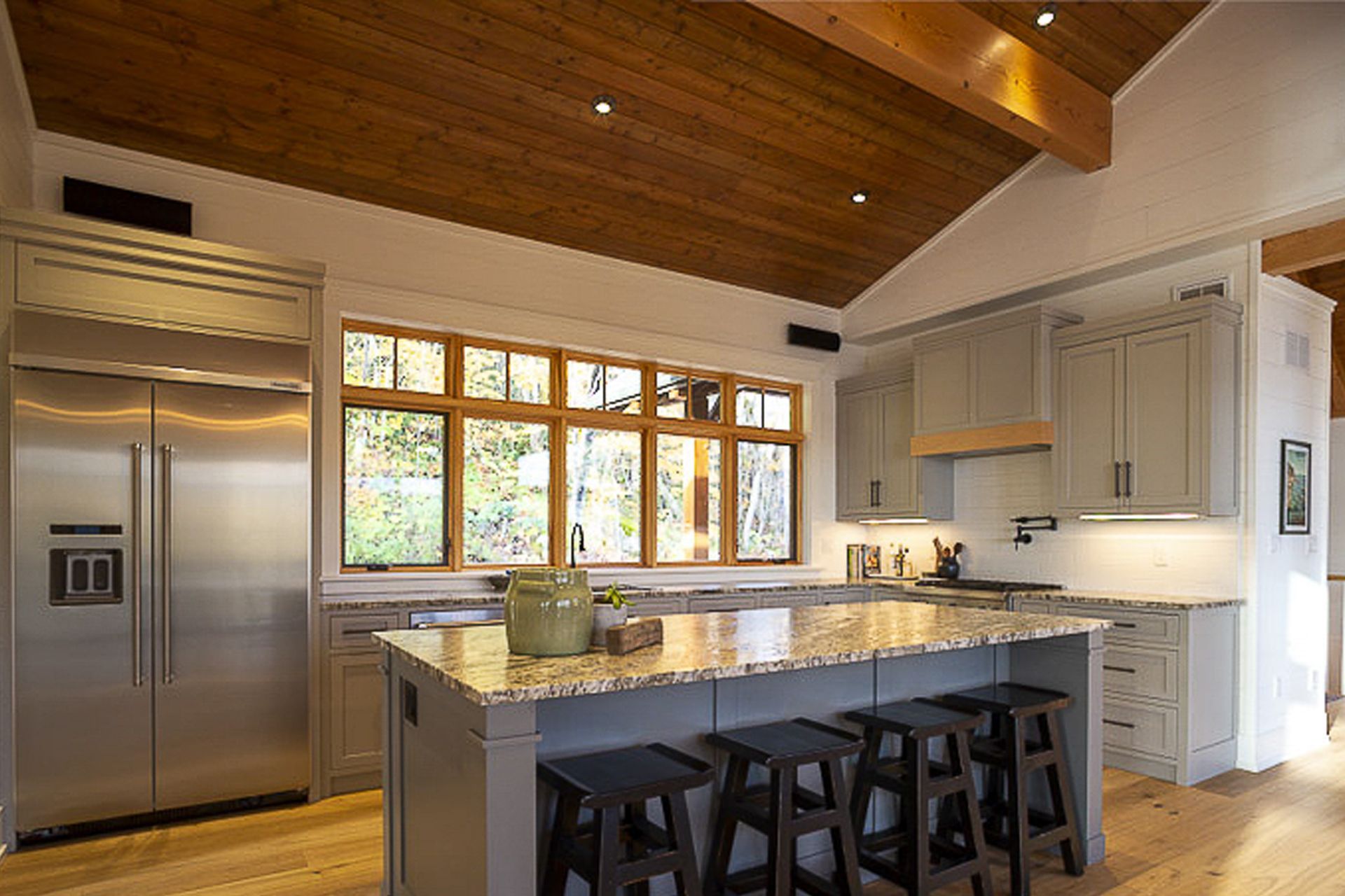 Large bright windows highlight this wide open kitchen  with double size fridge and a large, 4-seat island.