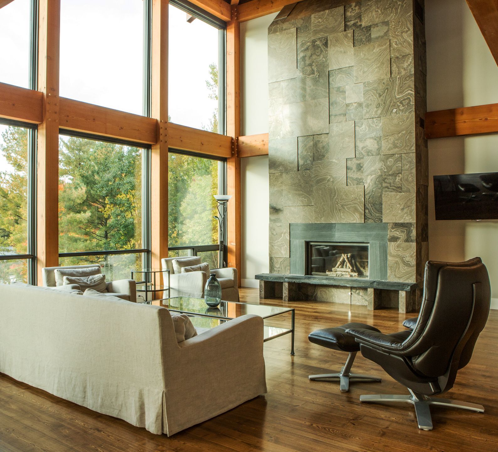 Open concept cottage showing large windows and a stone fireplace.