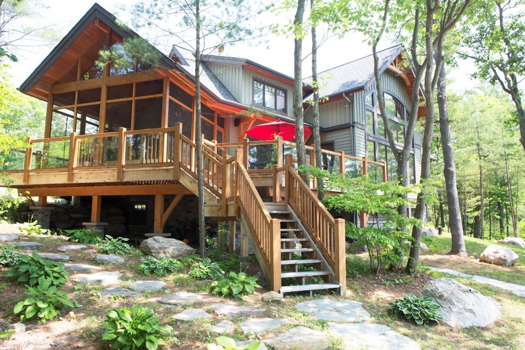 View of a traditional, Muskoka cottage showing stairs, railing surrounding the screened-in porch.