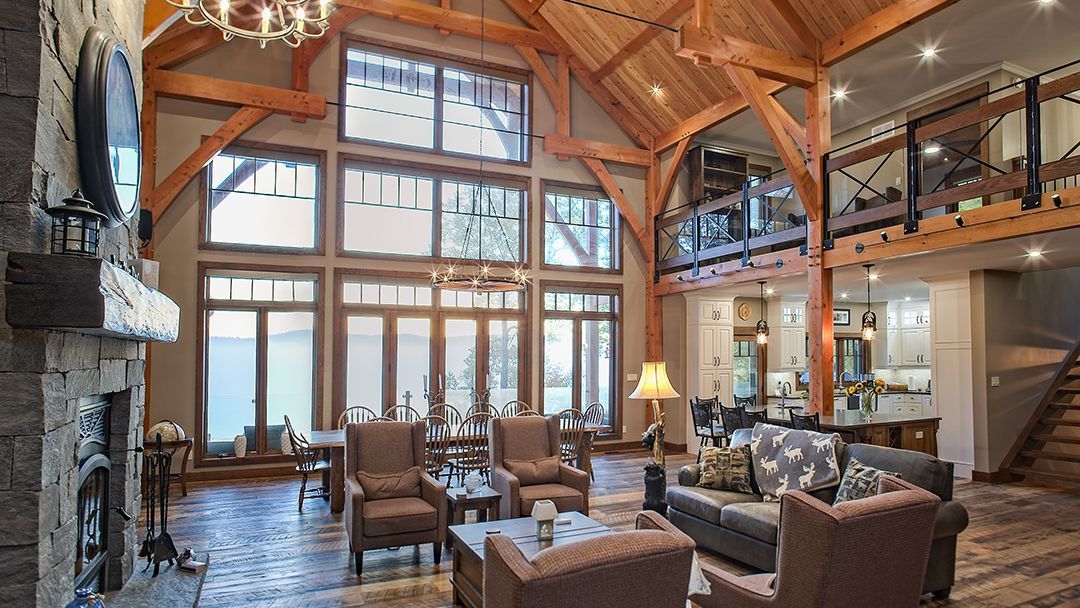 Large central room with exposed beams, huge windows, a second storey balcony with adjacent kitchen.