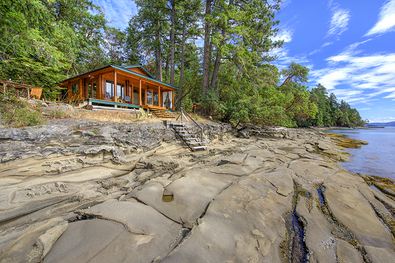 Single level cedar cottage on rocky shore