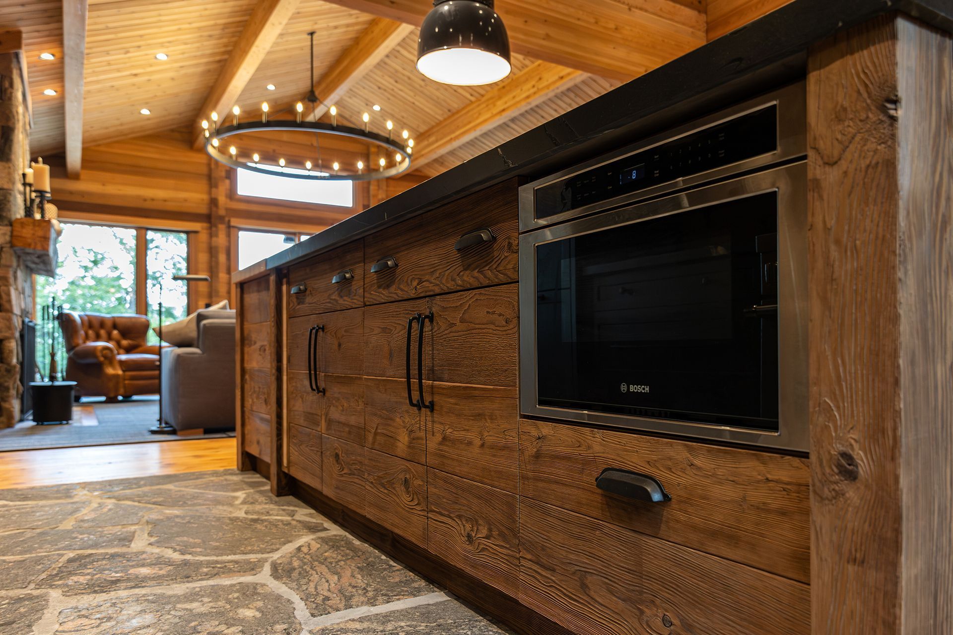 Low view of the rustic, wooden cabinets and slate flooring within the kitchen of a cedar cottage.