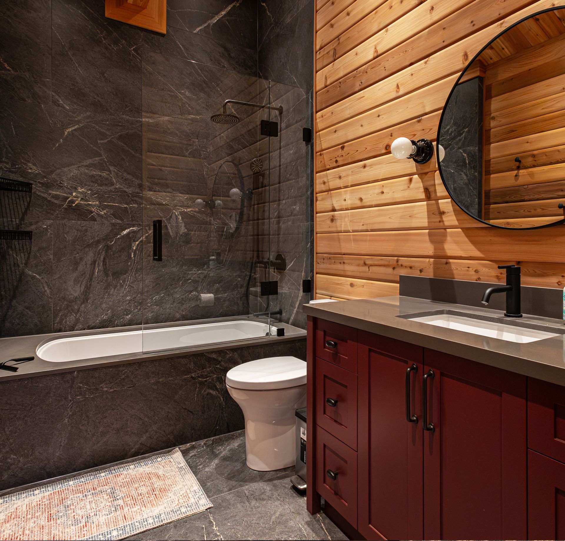 Cedar walls and black marble shower in a bathroom with slate floorings.