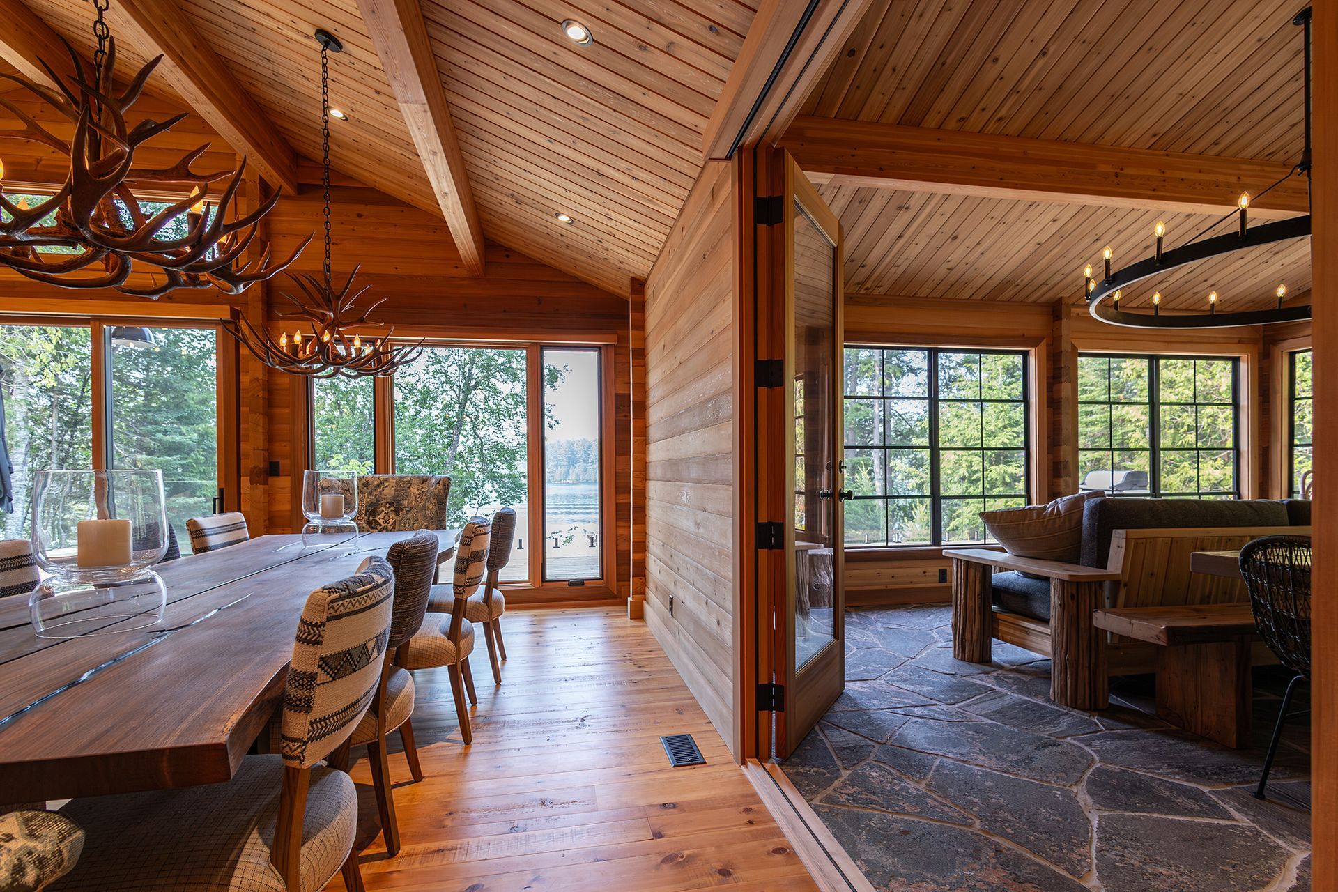 Two rooms inside a cedar cottage showing views of the lake and slate flooring.