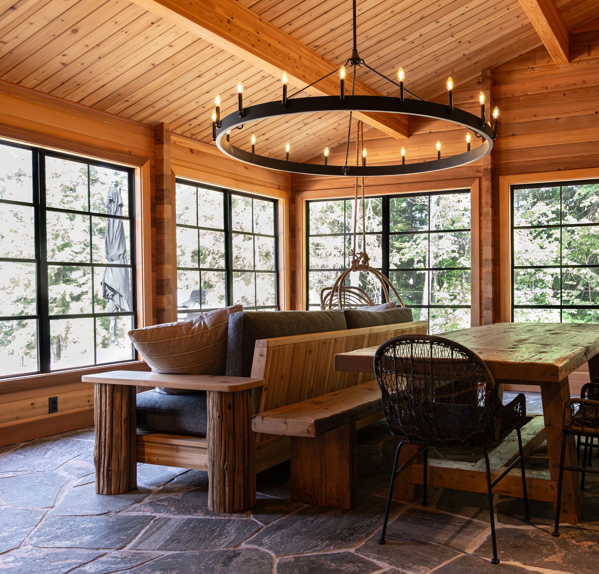 Interior of cedar cottage with expansive window views to the surrounding woods.