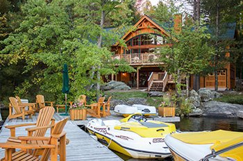 Watercraft, lakeside dock with Muskoka chairs in front of a custom cottage.
