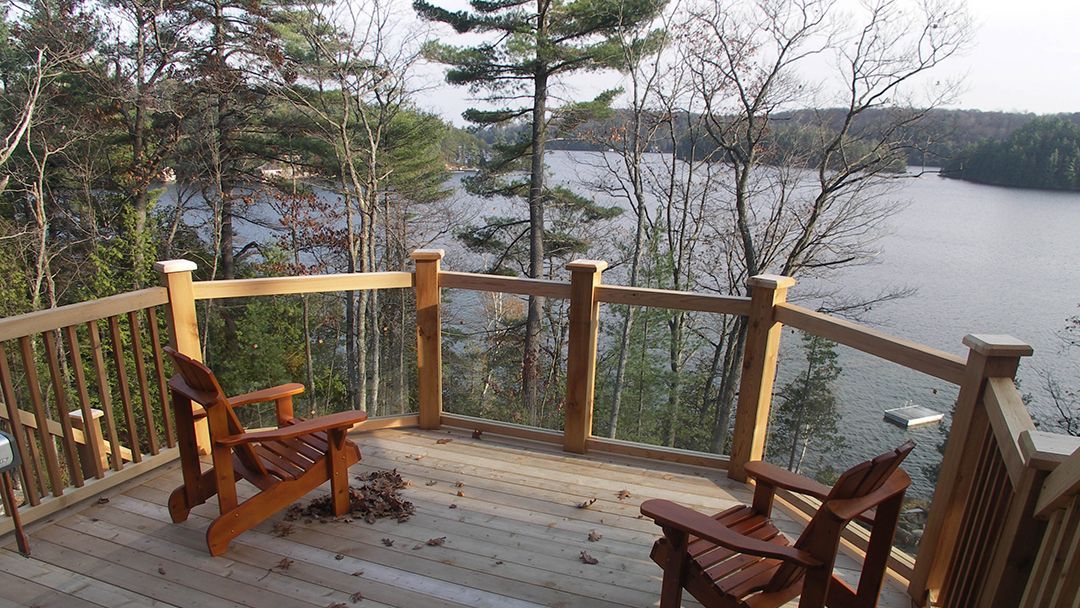 Cottage balcony is shown with a view to lakes and Muskoka islands.