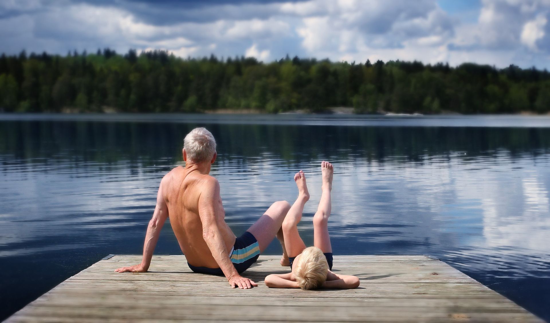 Grandfather with his grandson on a pier in a Muskoka lake.