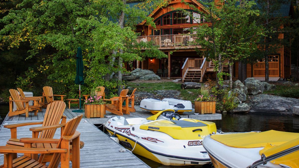 Custom Muskoka Cottage featuring a  yellow jet ski is docked at a dock in front of a house.