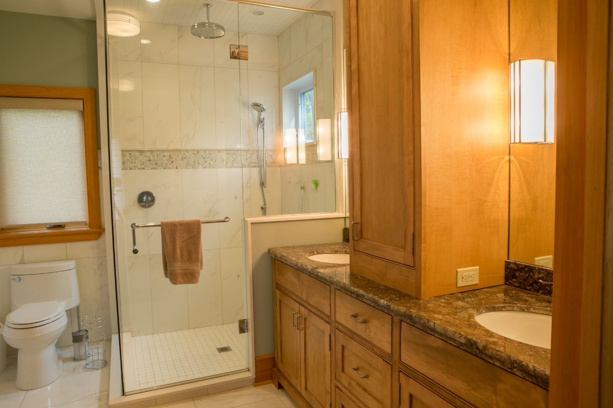 Custom Muskoka Cottage featuring a  bathroom with a walk in shower , sink , toilet and mirror.