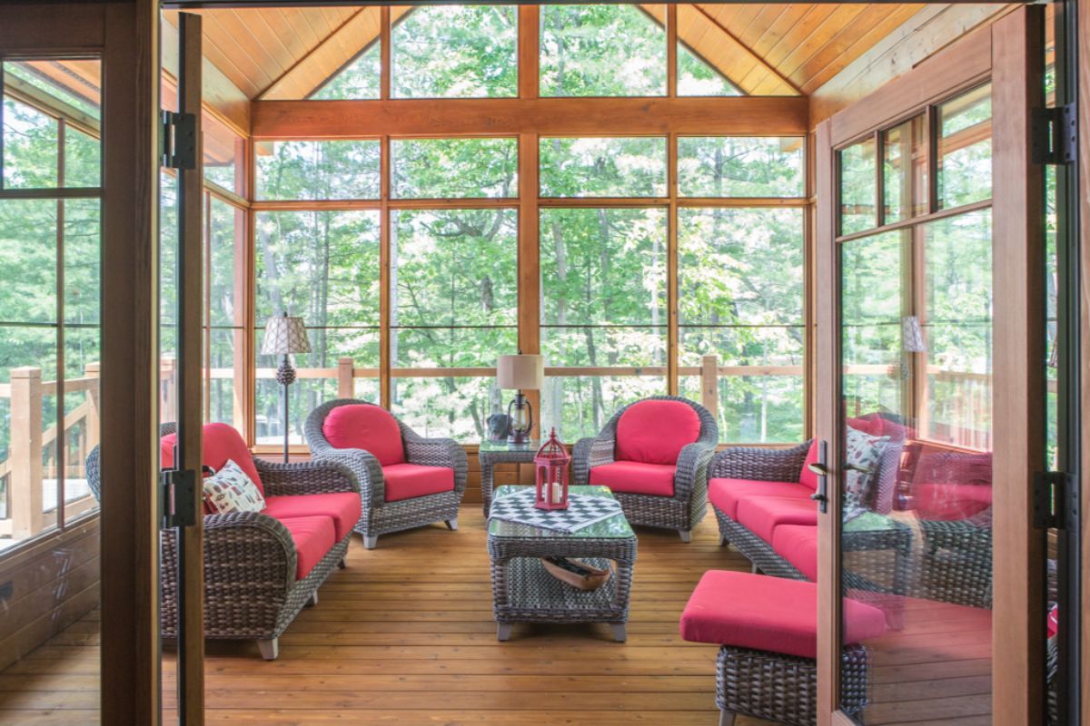 Custom Muskoka Cottage featuring a  screened in porch with wicker furniture and lots of windows.
