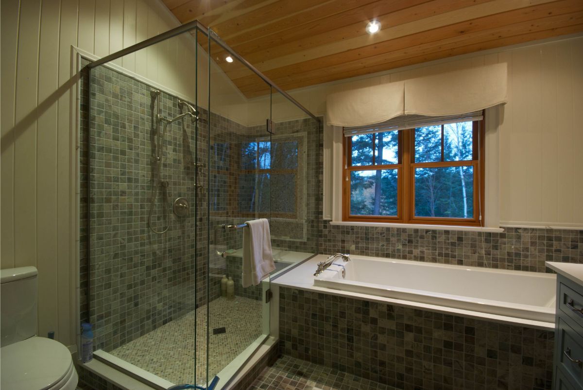 Custom Muskoka Cottage featuring a  bathroom with a tub , toilet , shower and window.