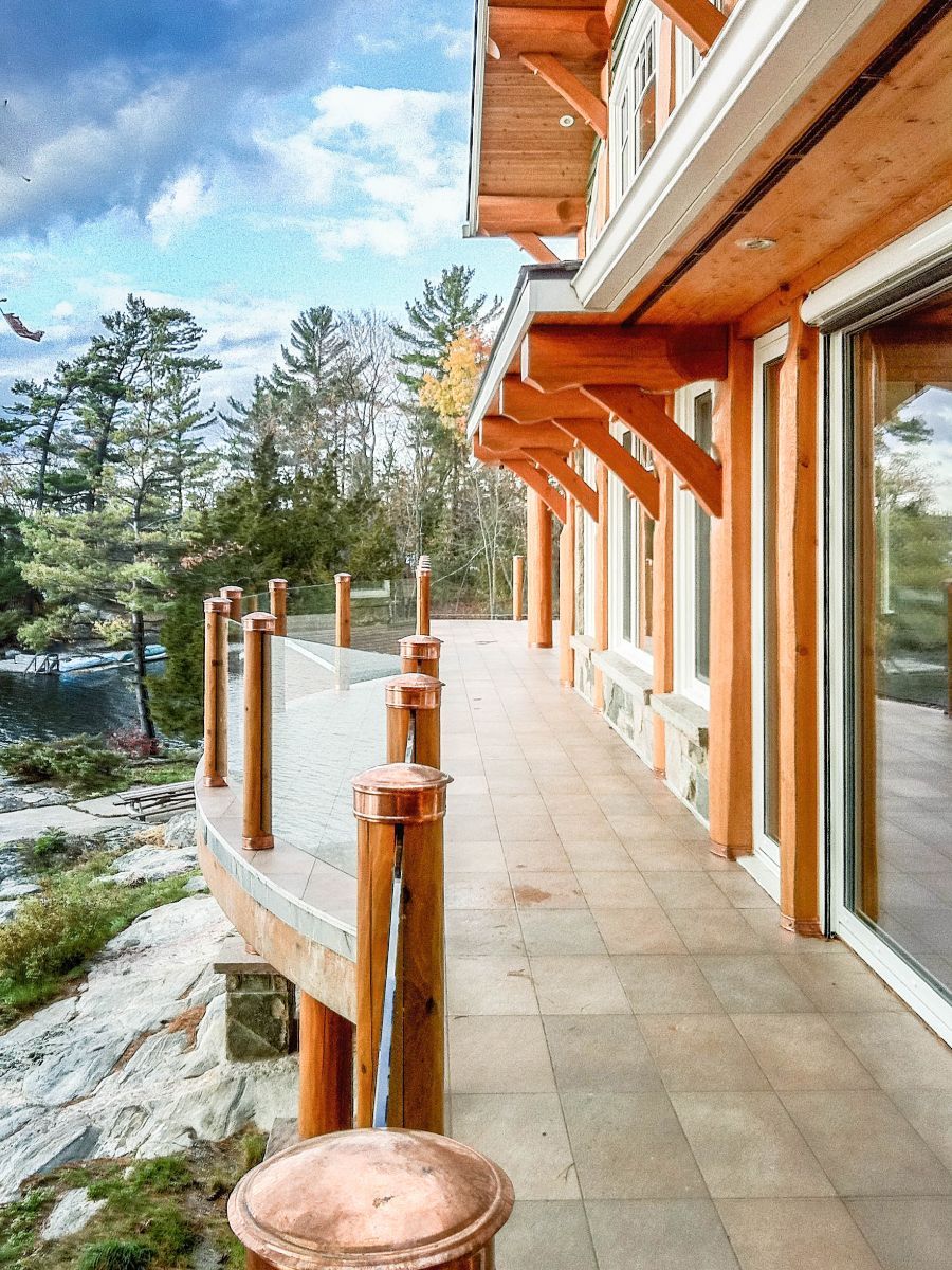 Custom Muskoka Cottage featuring a  large wooden house with a large deck and sliding glass doors