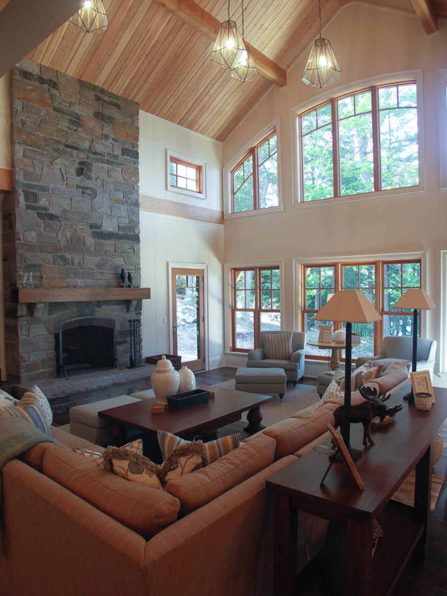 Custom Muskoka Cottage featuring a  living room with a stone fireplace and lots of windows