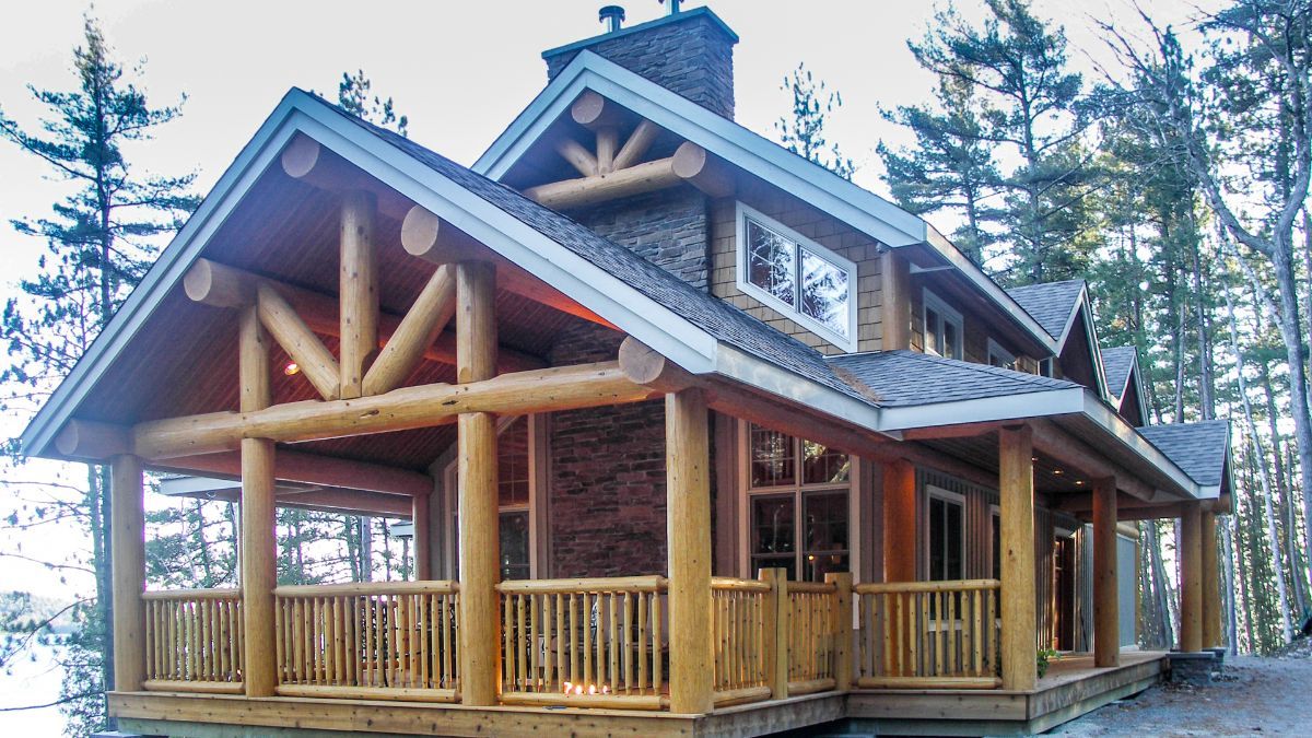 Custom Muskoka Cottage featuring a  large log cabin with a large porch in the woods