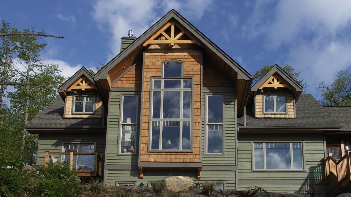 Custom Muskoka Cottage featuring a  large house with a lot of windows is sitting on top of a hill