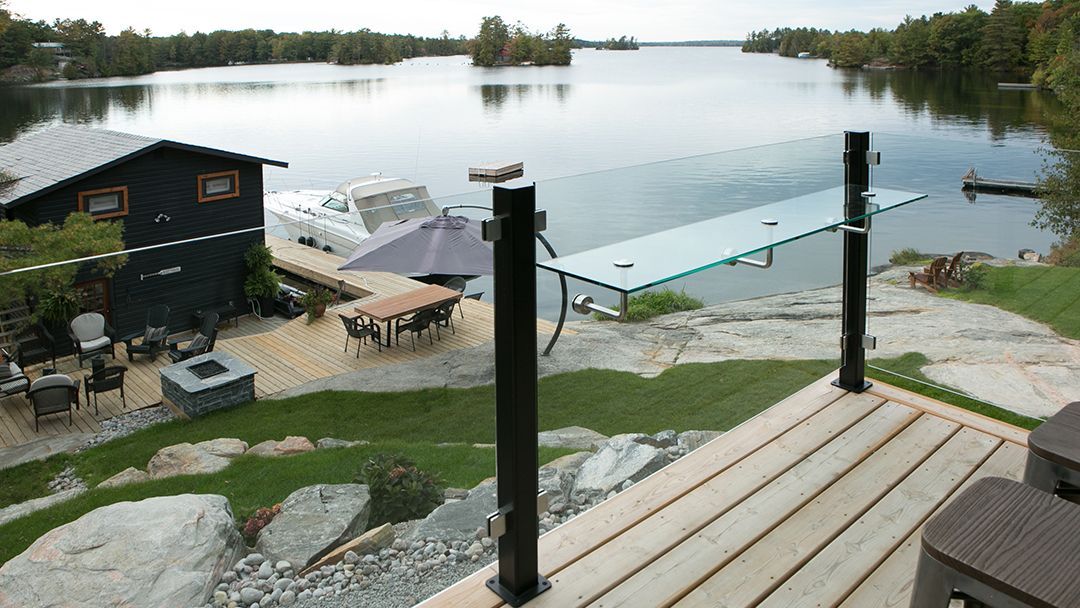 Cottage balcony is shown with a view to the boat, boathouse, deck and firepit.