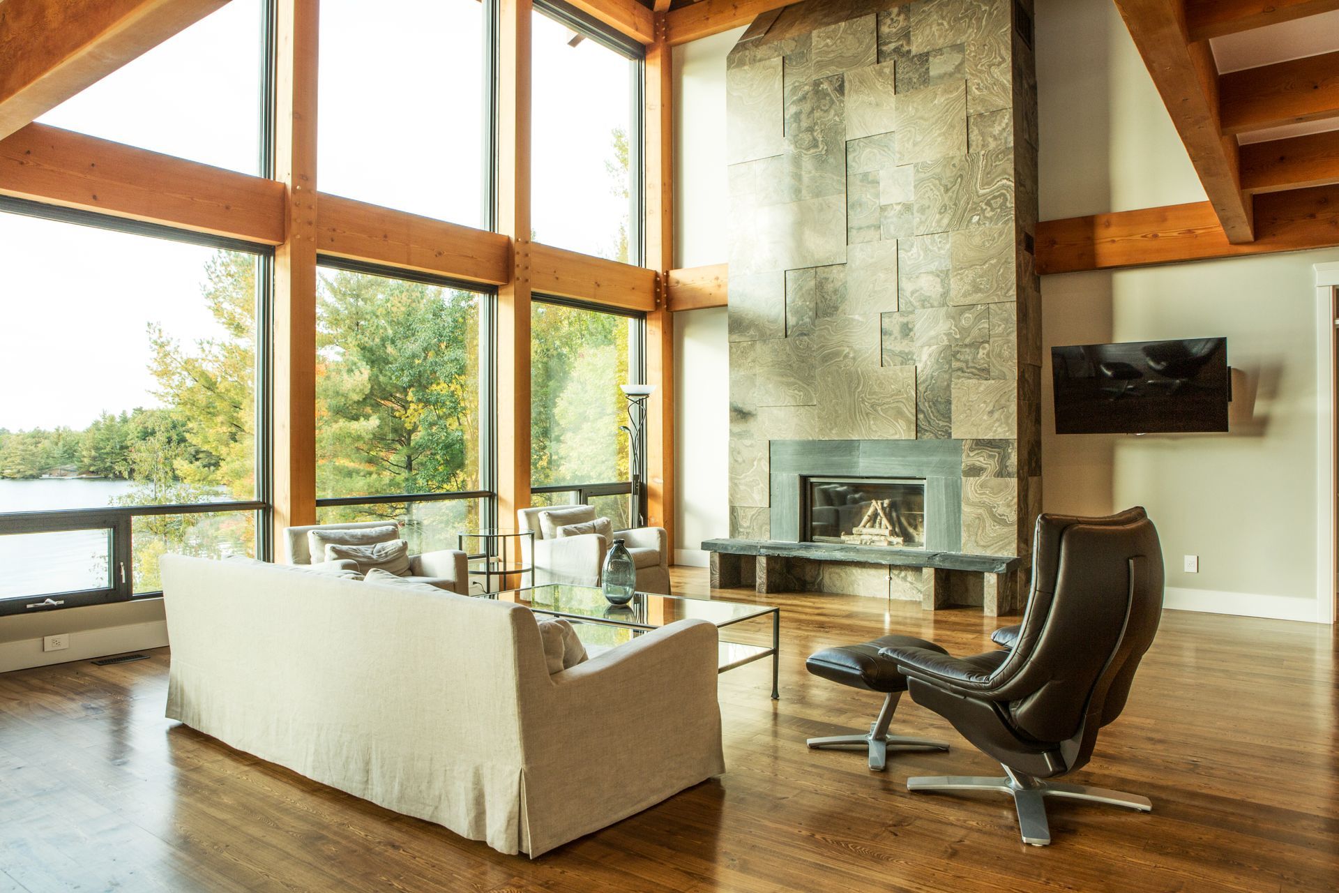 Modern living room with oversized windows and tall tiled fireplace.