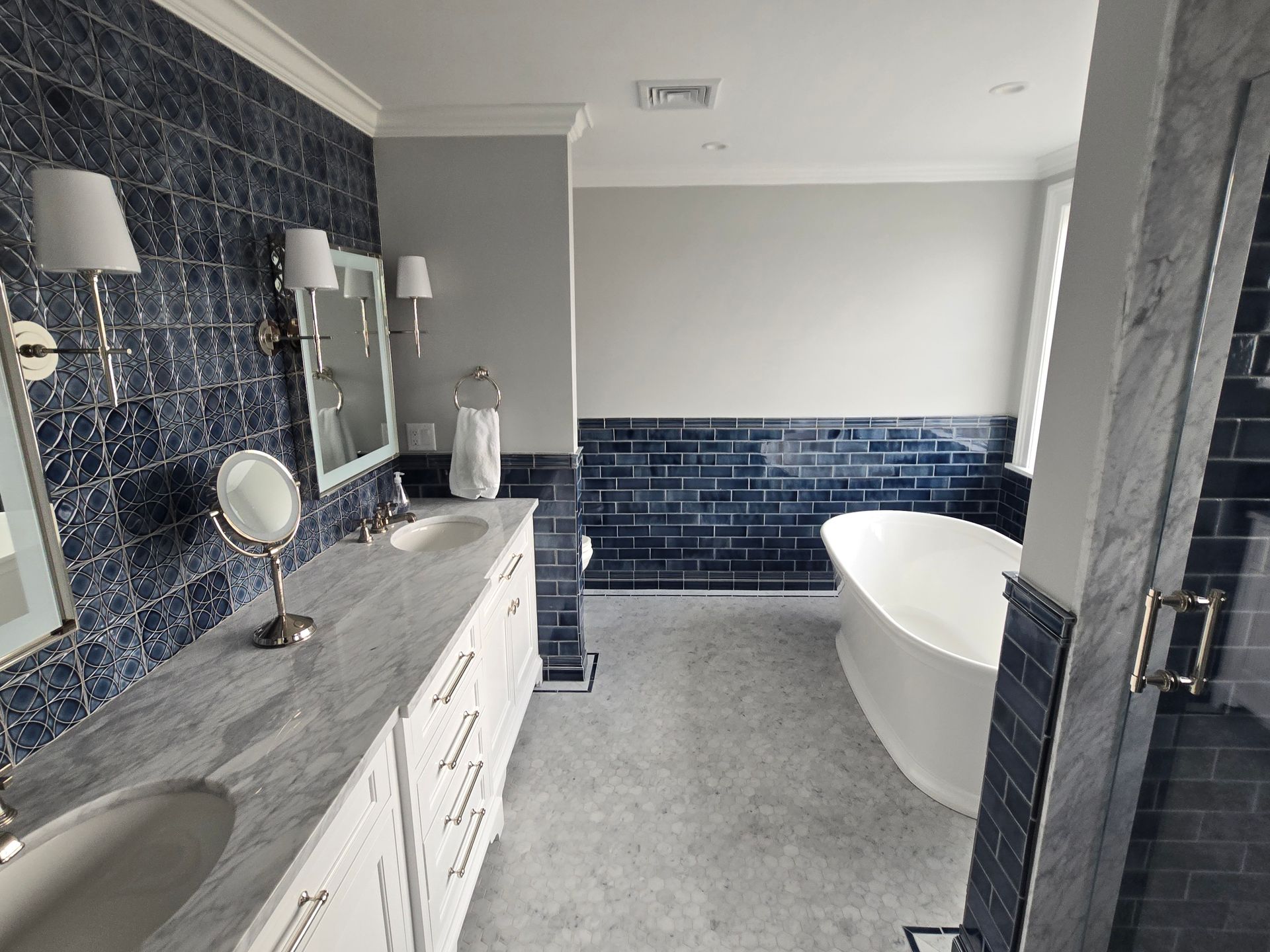 A bathroom with a bathtub , sinks , mirrors and blue tiles.