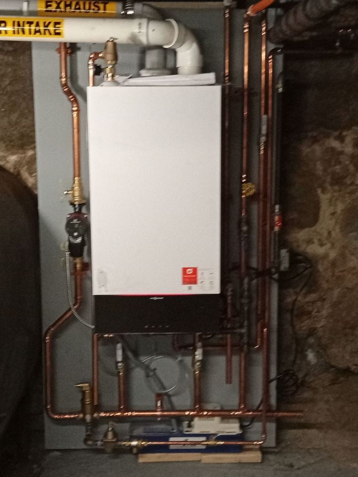 A boiler with copper pipes and a yellow sign that says exhaust