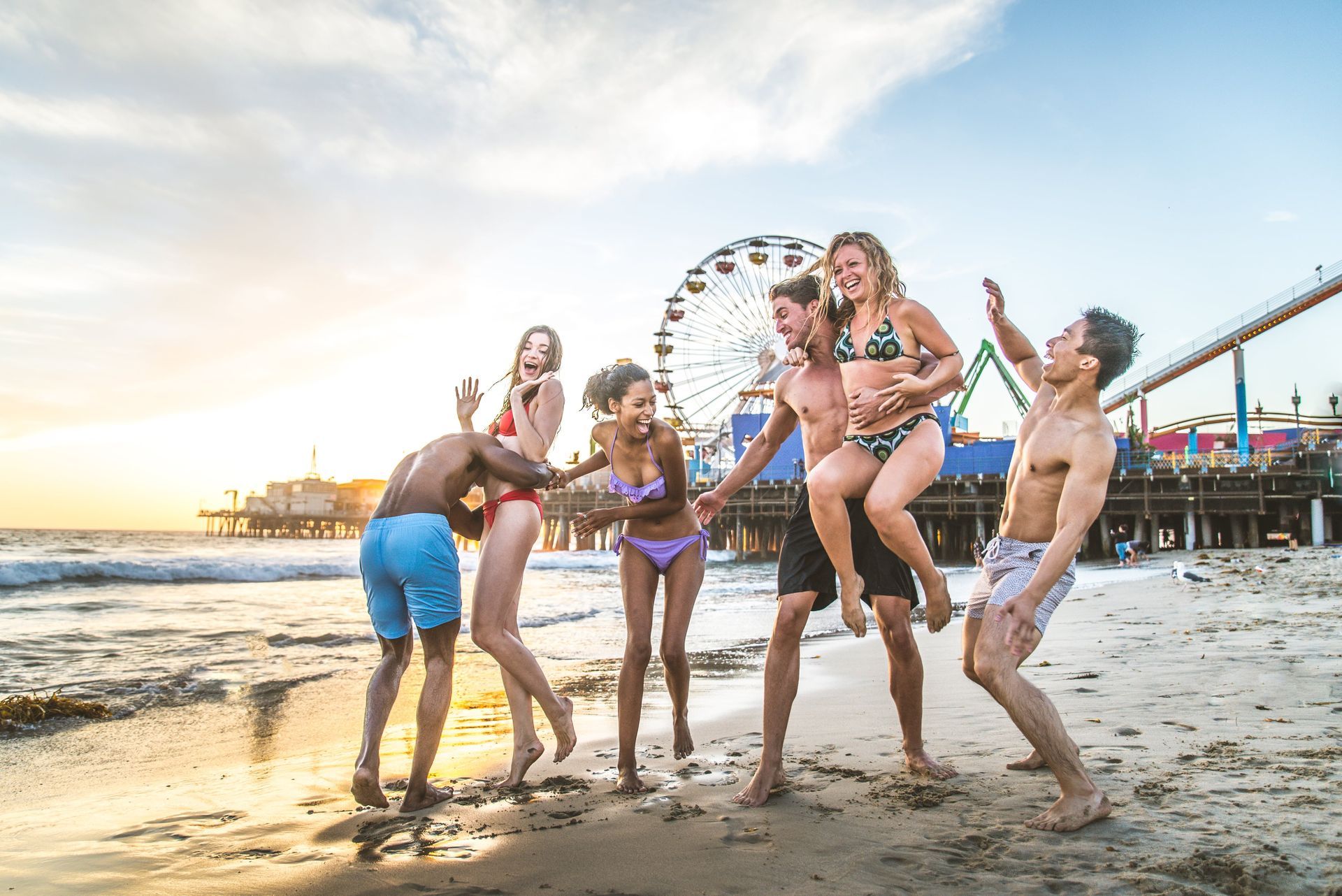 a group of people are dancing on the beach in front of a ferris wheel in Myrtle beach