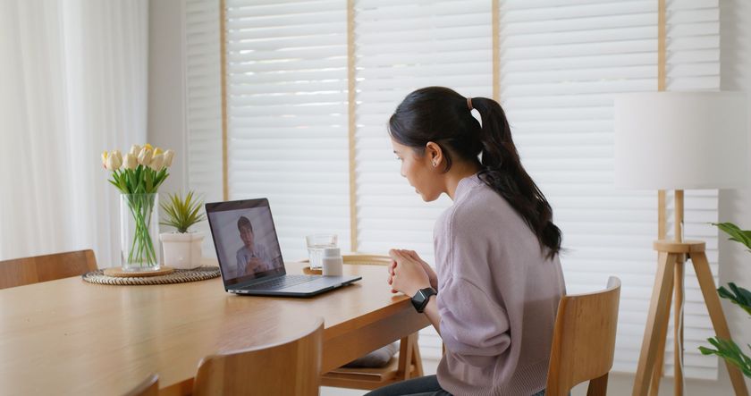 A woman is sitting at a table using a laptop computer.