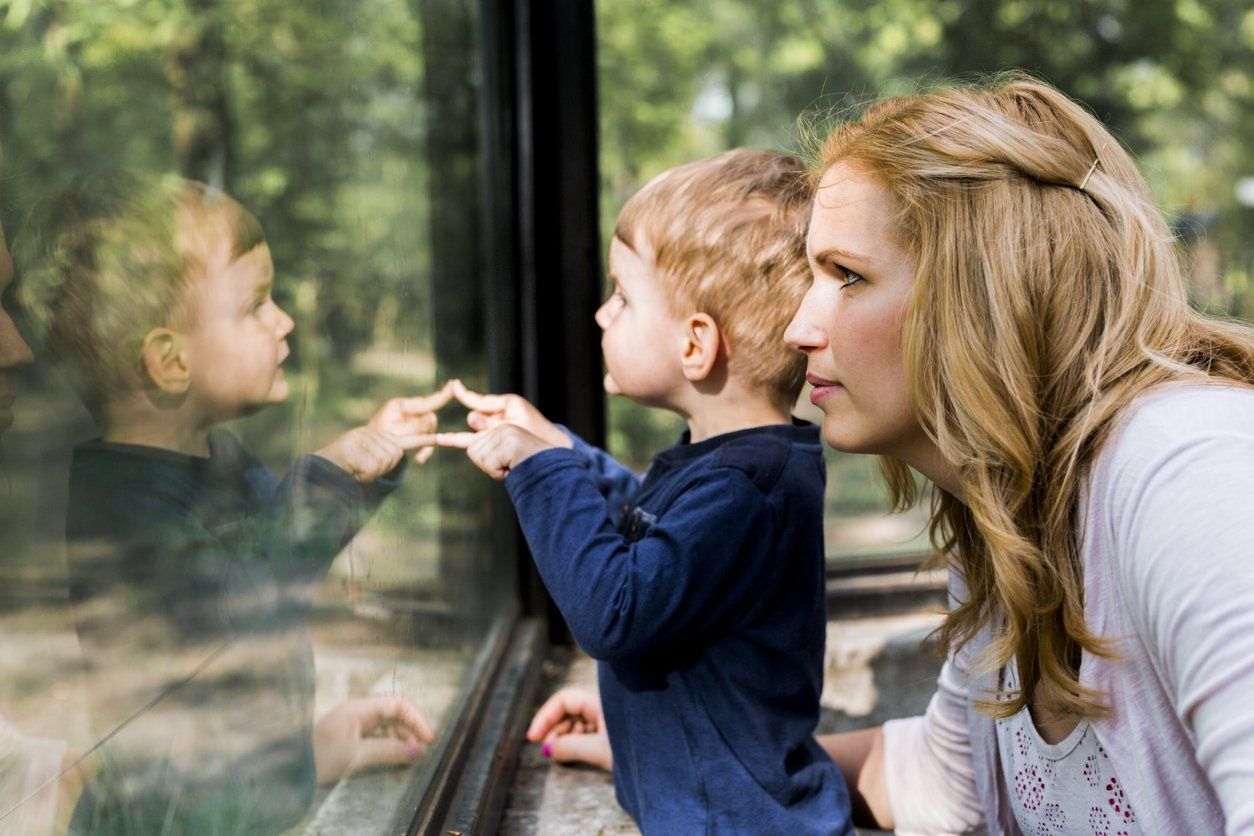Mom and son looking through glass.