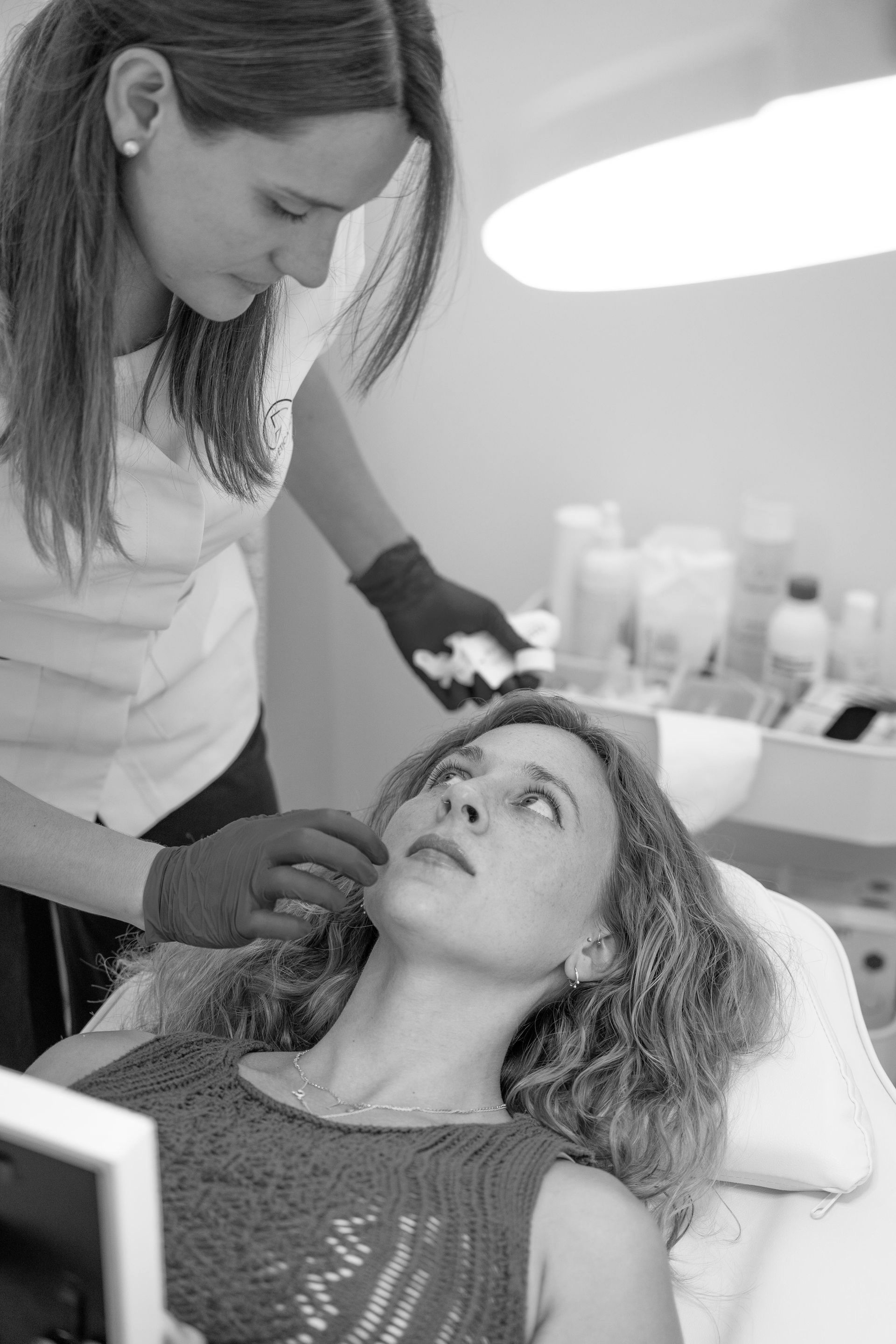 Una mujer está recibiendo un tratamiento facial en una foto en blanco y negro.