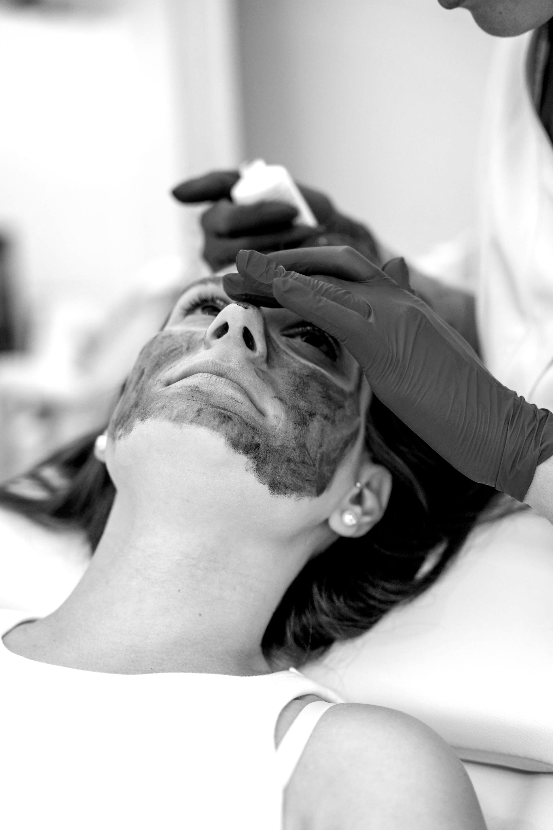 Una mujer está recibiendo un tratamiento facial en una foto en blanco y negro.