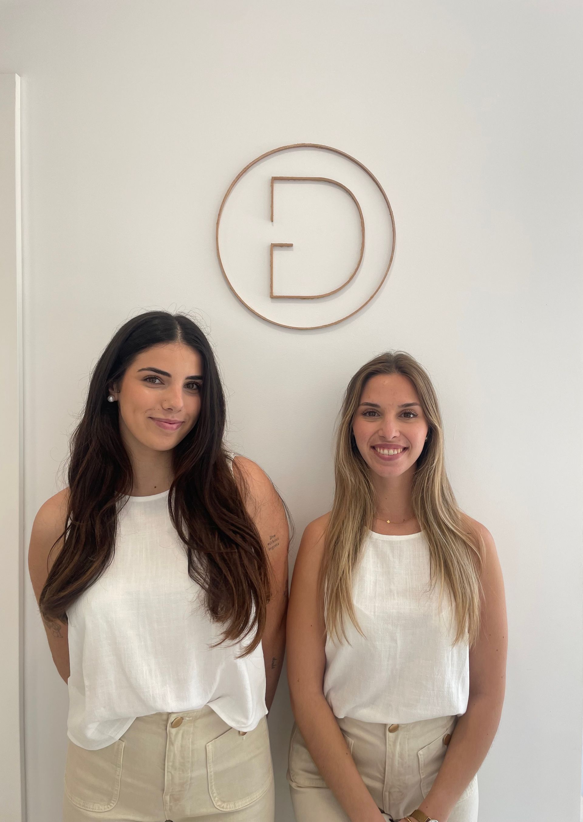 Dos mujeres están paradas una al lado de la otra frente a una pared blanca.