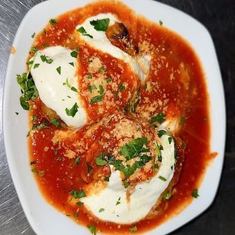 Plate of Italian food: Eggplant, tomato sauce, cheese, and parsley garnish.