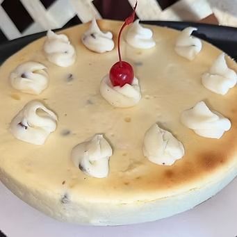 Cheesecake with cream dollops and a cherry on top.