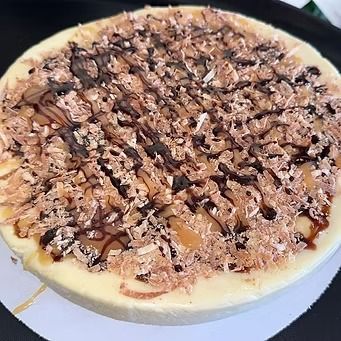 Cheesecake with shredded coconut and chocolate drizzle topping.