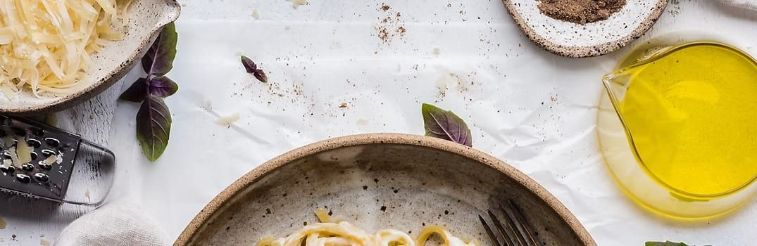 Overhead shot of pasta in a bowl with grated cheese, basil, lemon slices, and olive oil.