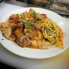 Chicken and sausage dish with vegetables and pasta on a white plate.