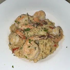 Shrimp risotto in a white bowl, garnished with parsley.