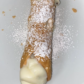 Cannoli on a white plate dusted with powdered sugar.