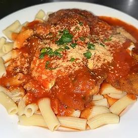 Chicken parmigiana with pasta in a white bowl, covered in tomato sauce and cheese.
