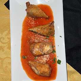 Fried ravioli in tomato sauce, sprinkled with cheese and parsley, on a white rectangular plate.