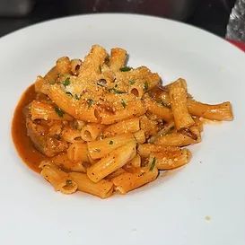 Pasta dish in tomato sauce on a white plate, topped with grated cheese.